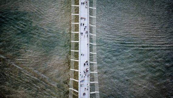 People walking across a bridge over water