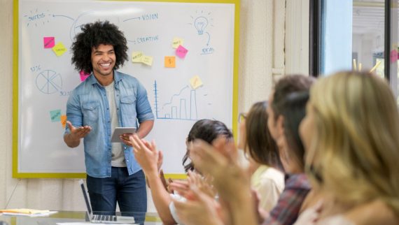 People clapping a male presenting his work