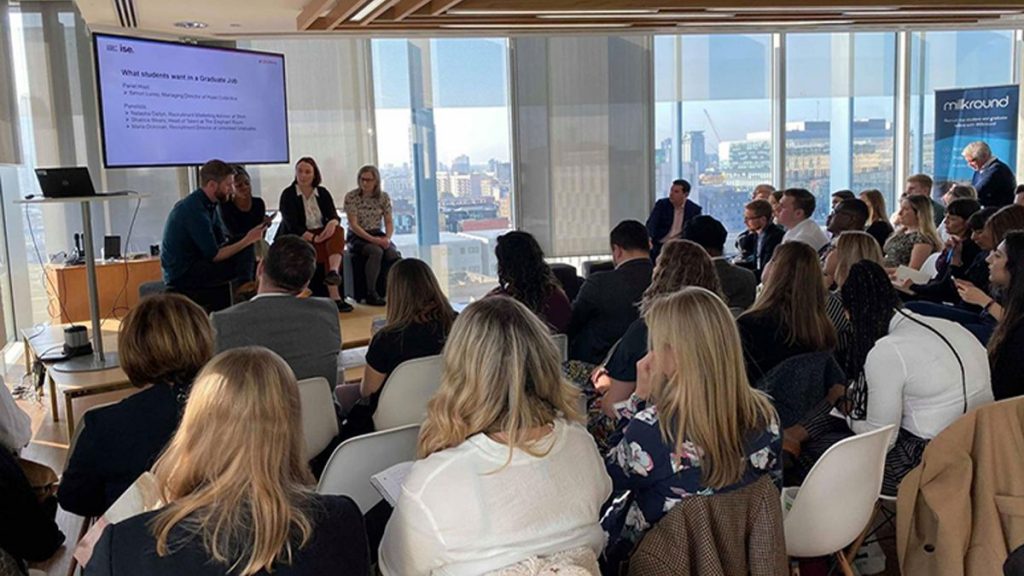 Adults listening to a panel discussion at an event.